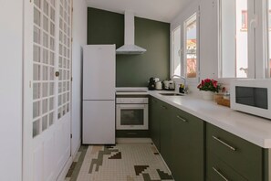 Eine kleine Küche mit Kühlschrank, Backofen und Mikrowelle.