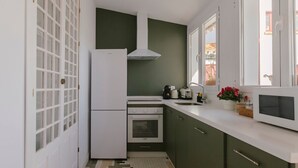 A compact kitchen with a refrigerator, oven, and microwave. - Hacienda Clavero Seven Deluxe Apartment: (Málaga)