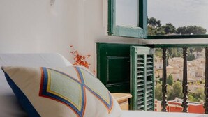 A room with a view of a cityscape through a window with a green frame.