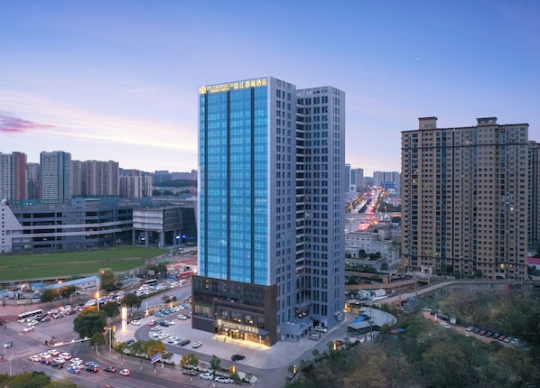 A high-rise hotel with a modern glass facade, surrounded by other buildings and a busy street.