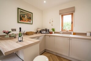 Une cuisine moderne dotée d’un plan de travail en bois, d’un évier, d’une fenêtre offrant une belle vue et d’une décoration murale.