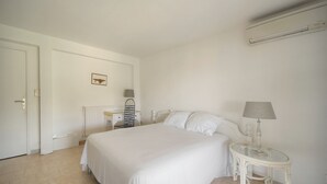 Et soveværelse med seng, natbord, lampe og en radiator.