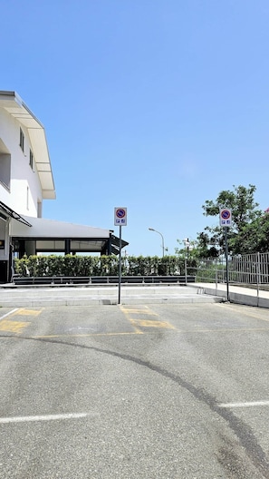 A parking area with no parking signs, a building with a covered entrance, and a clear blue sky.