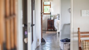 Un pasillo que conduce a un dormitorio con cama, mesita de noche y ventana.