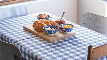 A breakfast setting with bread, eggs, butter, and jam on a checkered tablecloth.