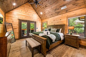 Een houten slaapkamer met een bed, nachtkastjes, een bankje en een televisie.