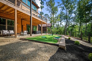 A modern wooden building with a deck and outdoor seating area. - Putts & Pines | King Suites with Putt-Putt, Pool, Golden Tee, Buck Hunter (Sevierville)