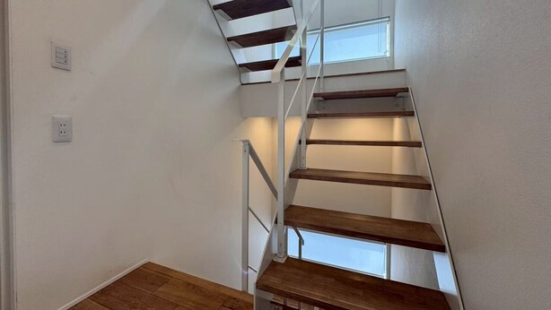 A staircase with wooden steps and white railings, leading to a landing with a window.