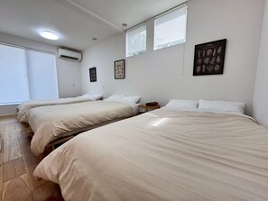 Ett hotellrum med tre sängar, ett fönster och en väggmonterad luftkonditioneringsanläggning.