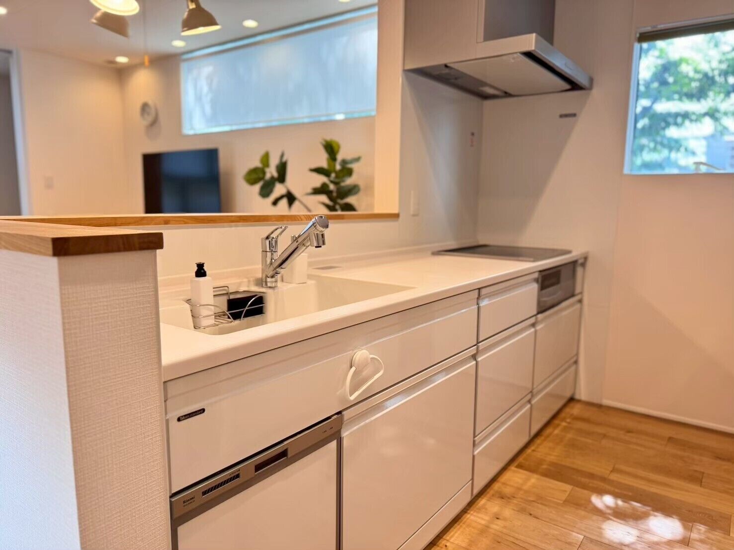A modern kitchen with a white countertop, stainless steel sink, and a built-in oven.
