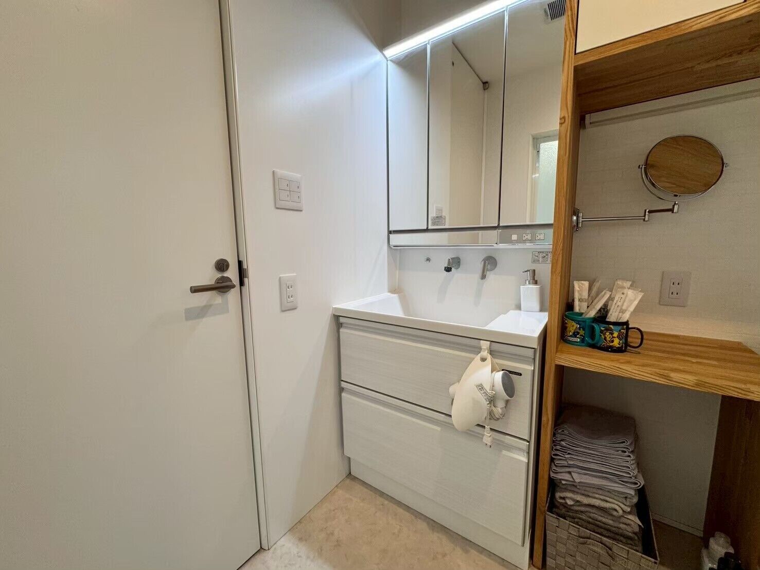 A compact bathroom with a white sink, mirror, and storage cabinet.