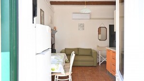 Ett kompakt bostadsutrymme med en matplats, en soffa och ett litet kök.