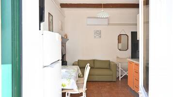 A compact living space with a dining area, a sofa, and a kitchenette.