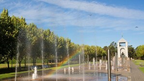 A park with a fountain, a rainbow, and a gazebo. - Modern Apartment Near Stadium & Shops (Lidcombe)
