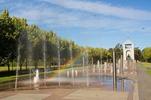 A park with a fountain, a rainbow, and a gazebo. - Modern Apartment Near Stadium & Shops (Lidcombe)