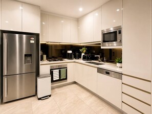 A modern kitchen with stainless steel appliances, a microwave, and a dishwasher. - Modern Apartment Near Stadium & Shops (Lidcombe)