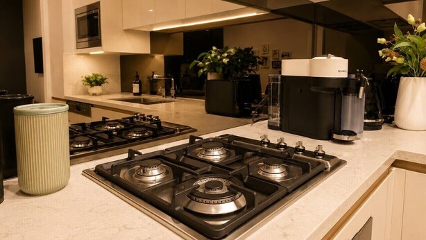A modern kitchen with a central gas stove, a microwave above it, and a coffee machine on the countertop. - Modern Apartment Near Stadium & Shops (Lidcombe)