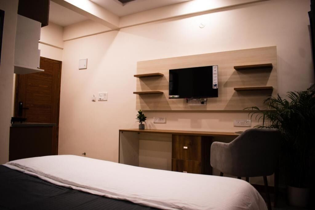 A hotel room with a bed, a desk with a television, and a chair.