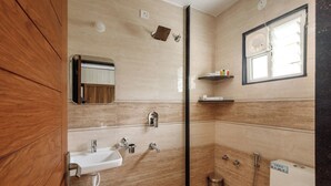 Een badkamer met een wastafel, spiegel, douche en raam.
