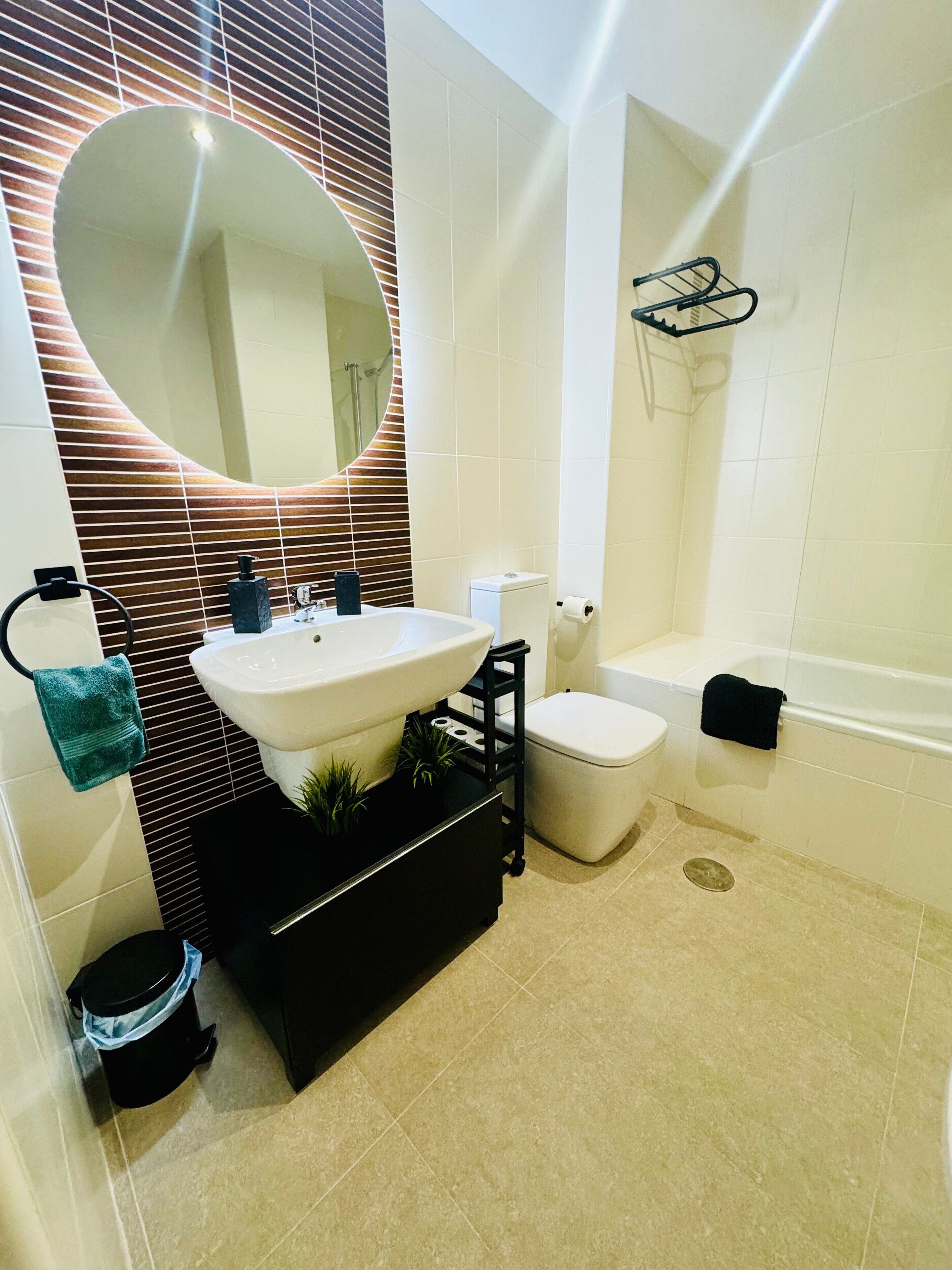 Ein modernes Badezimmer mit einem weißen Waschbecken, einer schwarzen Ablage und einer schwarzen Toilette.