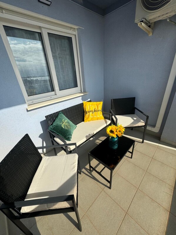 A balcony with two chairs, a small table, and a window with curtains.