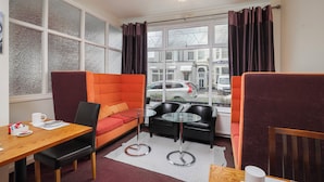 A modern room with a sofa, a dining table, and a small coffee table. - Devon Guest House (Blackpool)