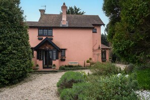 A traditional house with a pitched roof, a chimney, and a gravel pathway leading to the entrance.