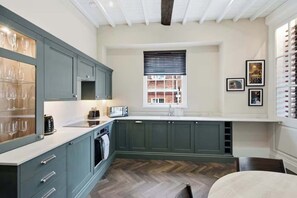 A kitchen with dark cabinets, a white countertop, a built-in oven, and a window with blinds. - Preacher's Yard Stylish Central York Apartment - Duplex 3 (York)