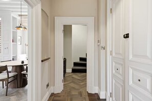 A hallway with a wooden herringbone floor, white doors, and a dining area with a table and chairs. - Preacher's Yard Stylish Central York Apartment - Duplex 3 (York)