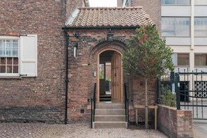 A brick building with a tiled roof, a wooden door, and a metal gate. - Preacher's Yard Stylish Central York Apartment - Duplex 3 (York)
