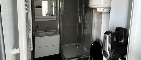 A compact bathroom with a toilet, sink, and shower.