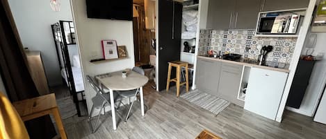 Una cocina compacta con microondas, estufa y armarios.