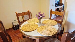 Une table de salle à manger ronde, surmontée de sets de table en fibres tressées, entourée de chaises en bois.