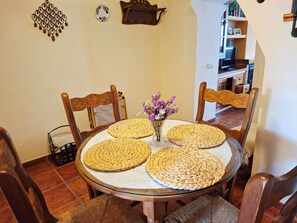 A round dining table with woven placemats, surrounded by wooden chairs. - Casa Luciíta: Cozy, with a fireplace, patio, and BBQ. Near Marbella (Ojén)