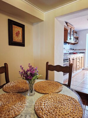 Un coin repas avec une table ronde, des sets de table en fibres tressées et des chaises.