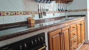 Une cuisine équipée d’une cuisinière, d’un four, de meubles en bois et d’un dosseret carrelé.