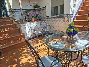 A patio area with a glass table and chairs, a bicycle, and potted plants. - Casa Luciíta: Cozy, with a fireplace, patio, and BBQ. Near Marbella (Ojén)
