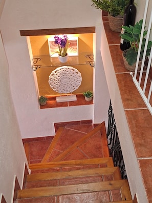A wooden staircase with a white railing, leading to a landing with a decorative white wall and a small potted plant. - Casa Luciíta: Cozy, with a fireplace, patio, and BBQ. Near Marbella (Ojén)