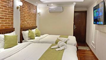 Una habitación de hotel con dos camas, una pared de ladrillo, un equipo de aire acondicionado y una televisión en la pared.