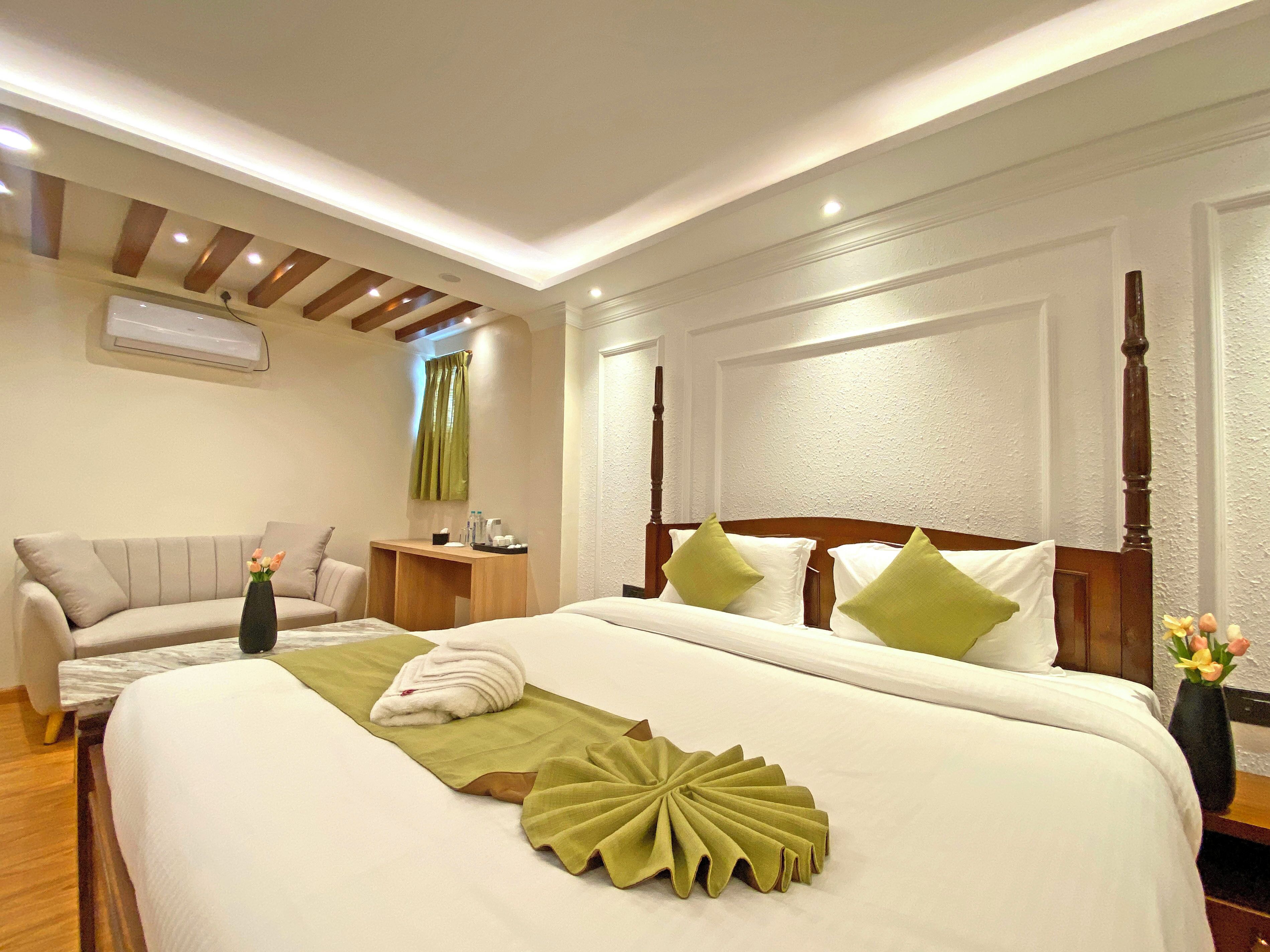 A hotel room with a large bed, a sofa, a desk, and a nightstand.