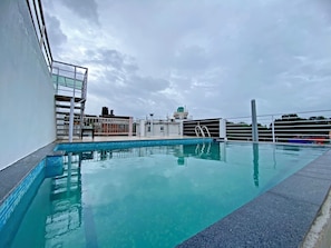 Una piscina en la azotea con vistas despejadas al cielo y edificios circundantes.