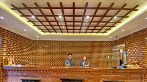 Een receptiebalie met een bakstenen achtergrond, een plafond met een rasterpatroon en decoratieve details.
