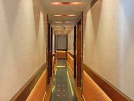 Ein Hotelkorridor mit Teppichboden, Holztüren und Einbaustrahlern.
