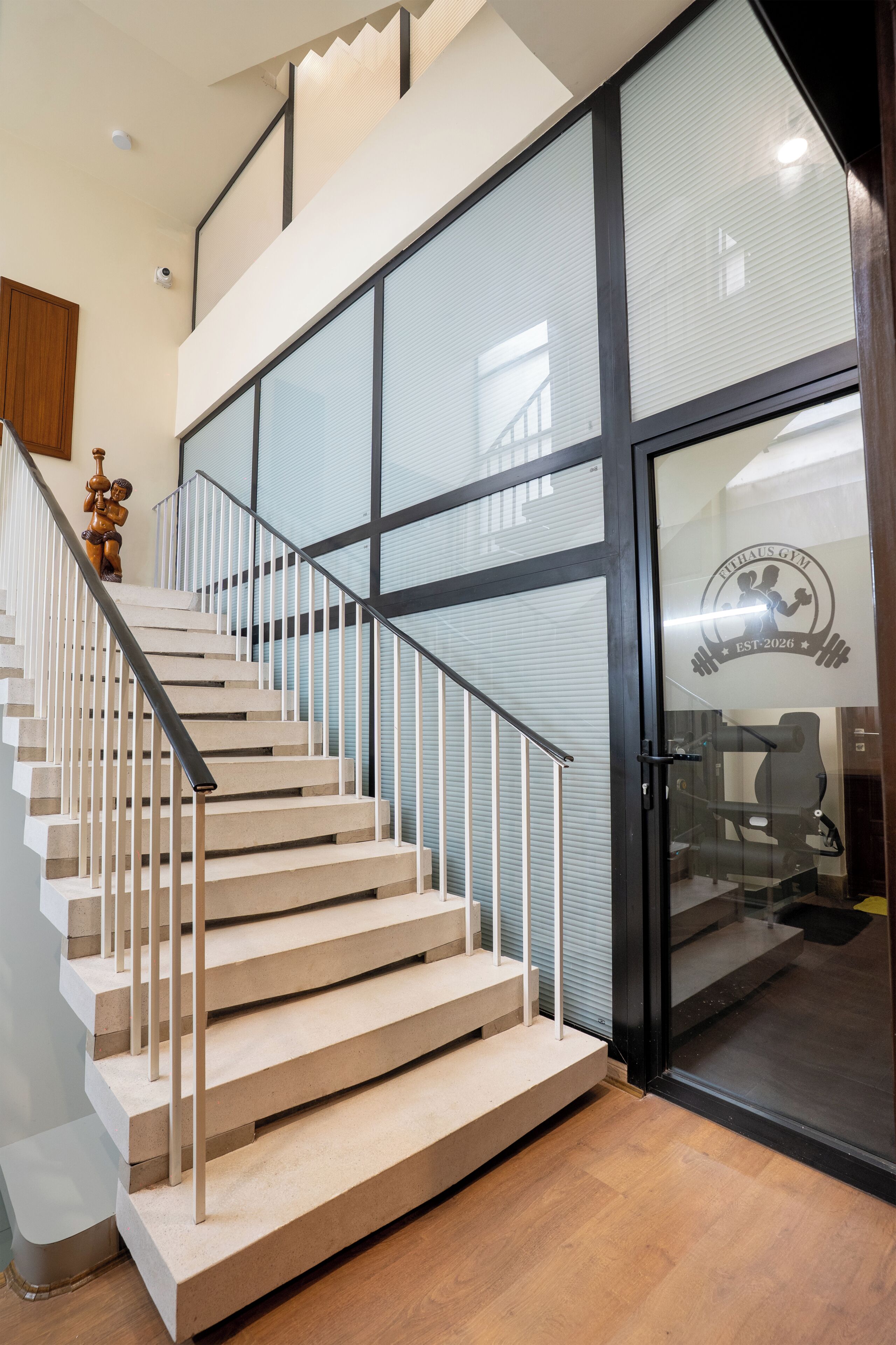 Una escalera moderna con una puerta de vidrio que da acceso a un gimnasio.