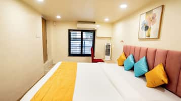 Una habitación de hotel con una cama, un cabecero tapizado en rojo y una ventana con persianas.