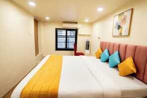 Una habitación de hotel con una cama, un cabecero tapizado en rojo y una ventana con persianas.