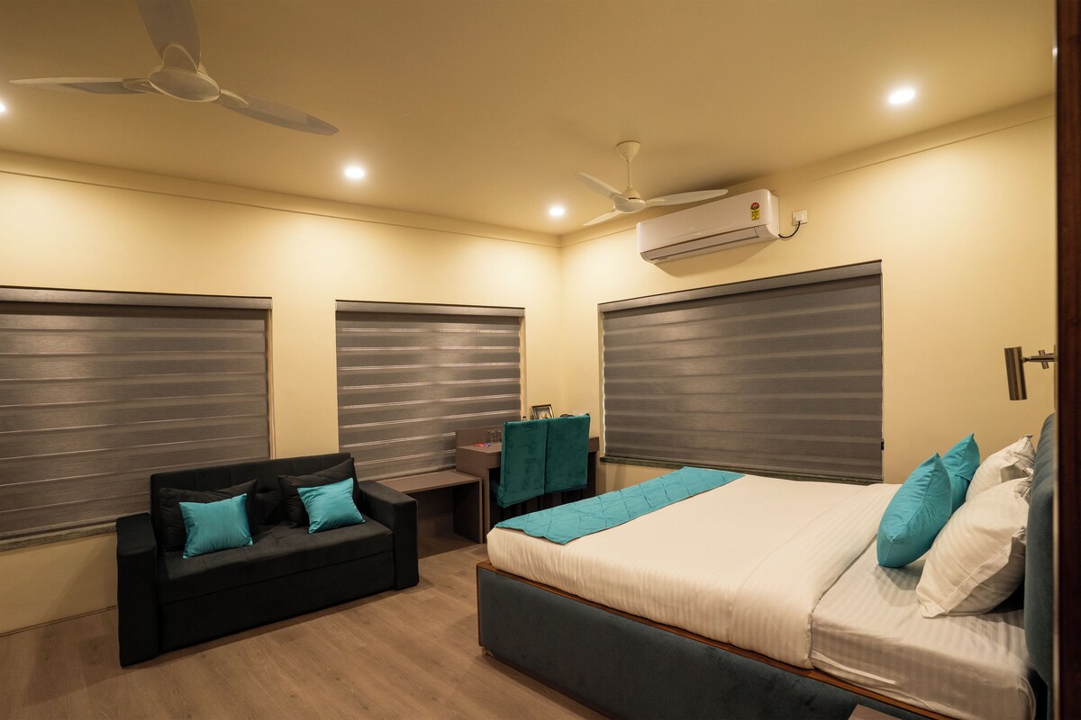 A bedroom with a bed, a sofa, a desk, and a ceiling fan.