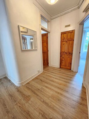 Un passadís amb terres de fusta, parets blanques i dues portes de fusta.