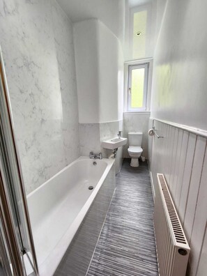 A bathroom with a bathtub, sink, and toilet. - Two-bed aparetment near Edinburgh city centre (Edinburgh)