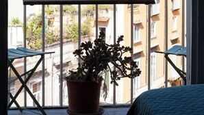 A balcony with a potted plant, a wooden ledge, and a view of buildings. - Bellavista Relais (Napoli)
